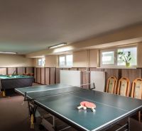 Pingpongový a kulečníkový stůl v herně hotelů a penzionů s dřevěným dekorem.