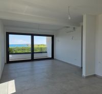 Obývací pokoj ve 4-pokojovém bytě s velkým oknem a výhledem na moře.