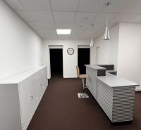 Kanceláře s recepcí, hodinami a skříňkami, s podlahou s dřevěným dekorem.