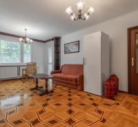 Obývací pokoj s pohovkou, stolkem a podlahou s dřevěným dekorem ve 3pokojovém bytě.