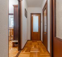 Chodba s podlahou s dřevěným dekorem v 3-pokojovém bytě, vedoucí do místnosti.