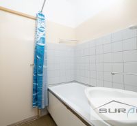Koupelna s vanou a modrým sprchovým závěsem ve 4pokojovém bytě.