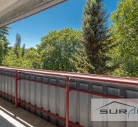 Balkon ve 4pokojovém bytě s výhledem na zeleň a modrou oblohu.