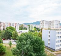 Výhled z 3pokojového bytu v Nitře na panelové domy a parkoviště s automobily.