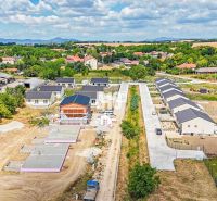 Výstavba rodinných domů v Nitře obklopená zelenou krajinou a dalšími nemovitostmi.