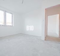 Interiér rodinného domu s bílými stěnami a betonovou podlahou.