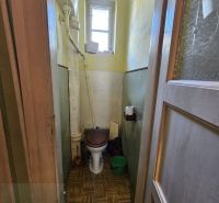 Toaleta v 2-pokojovém bytě s oknem a podlahou s dřevěným dekorem.