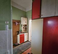 Vstupní chodba 2pokojového bytu se zelenými stěnami a skříňkami v červeno-bílé barvě.