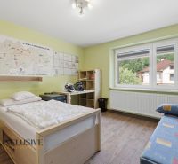 Pokoj v rodinném domě s mapou na stěně, postelí a podlahou s dřevěným dekorem.
