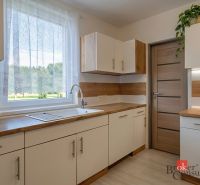 Kuchyně ve 4-pokojovém bytě s podlahou s dřevěným dekorem a výhledem do zahrady.