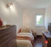 Ložnice ve 4pokojovém bytě s podlahou s dřevěným dekorem a jednoduchým vybavením.