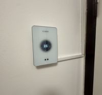 Termostat na stěně v 2-pokojovém bytě, teplota nastavena na 22 °C.