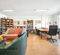 Knihovna s pohodlným sezením a psacími stoly na podlaze s dřevěným dekorem.