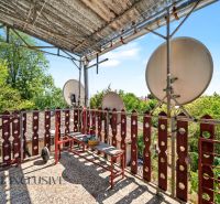 Balkon rodinného domu v Bodze se satelity a zelení v pozadí.