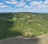 Zalesněné zemědělské a lesní pozemky v okolí Tornale pod modrou oblohou.