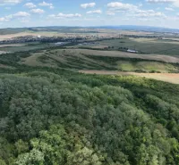 Krajina v Tornaľi se smíšenými zemědělskými a lesními pozemky pod jasnou oblohou.