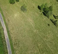 Letecký snímek krajiny u Staré Ľubovně, zvýrazňující zelené louky a stromovou scenérii.