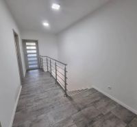 Chodba v rodinném domě se schodištěm a keramickou dlažbou.