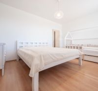Ložnice s podlahou s dřevěným dekorem, manželská postel a dětská postel.