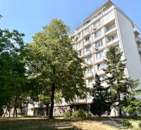Bytový dům na Piešťanské v Bratislavě - Novém Městě obklopený zelení a lavičkou.