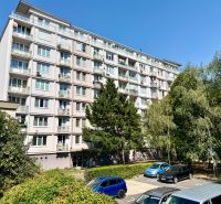 Bytový dům na Piešťanské ulici v Bratislavě - Nové Město obklopený zelení a parkovištěm.
