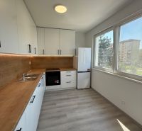 Kuchyně ve 3-pokojovém bytě s bílými skříněmi a podlahou s dřevěným dekorem.