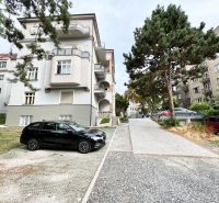 Bytový dům u ulice Palisády v Bratislavě - Staré Město, obklopený zelení a auty.