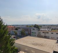 Pohled na městskou panorámu Lučence s budovami ze střechy 1-pokojového bytu.