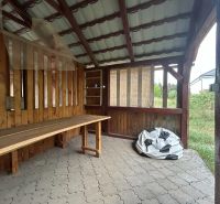Dřevěný přístřešek v Telinciach a 2-pokojový byt s kamennou podlahou v pozadí.