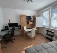 Interiér 3-pokojového bytu s podlahou s dřevěným dekorem, pracovním stolem a pohovkou.