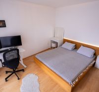 Ložnice s postelí, pracovním stolem a podlahou s dřevěným dekorem ve 4pokojovém bytě.