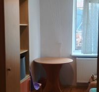 Pokoj v rodinném domě s podlahou s dřevěným dekorem, stolem a regálem.