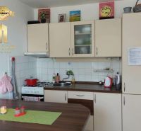 Kuchyně v 1-pokojovém bytě s podlahou s dřevěným dekorem a světlými skříňkami.