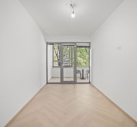 Bílá místnost se zaskleným balkonem a podlahou s dřevěným dekorem ve 4-pokojovém bytě.