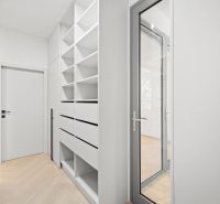 Chodba s vestavěnými regály a dveřmi ve 4pokojovém bytě s podlahou v dřevěném dekoru.
