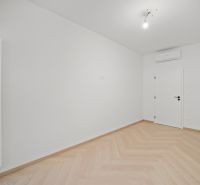 Světlý pokoj s bílými stěnami a podlahou s dřevěným dekorem.