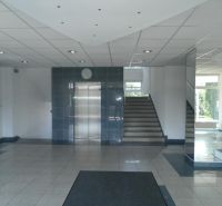 Kanceláře s výtahem a schodištěm, zrcadla odrážejí světlo, dlaždicová podlaha.