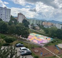 Pohled na barevné hřiště, hřiště a paneláky na Mateja Bela v Trenčíně.