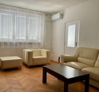 Obývací pokoj v 2-pokojovém bytě s krémovou sedačkou a podlahou s dřevěným dekorem.