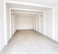 Interiér prostorné garáže s bílými stěnami a betonovou podlahou.
