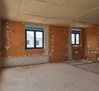 Interiér 3-pokojového bytu ve výstavbě s holými cihlovými stěnami a plastovými okny.