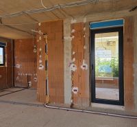 Rozestavěný 3-pokojový byt s cihlovými stěnami a elektroinstalací připravenou na montáž.