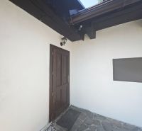 Vchod do chaty ve Španej Dolině s kamennou terasou a dřevěnými prvky.