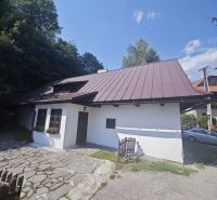 Rodinný dům ve Španí Dolině s kamenným chodníkem a dřevěným plotem obklopený přírodou.