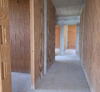 Interiér 4-pokojového bytu s holými cihlovými stěnami a cementovou podlahou.