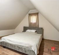 Podkrovní ložnice na chatě s postelí a podlahou s dřevěným dekorem.
