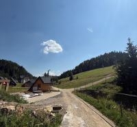 Rekreační pozemky v Litmanové se scenérií lesa a domů, modré nebe.