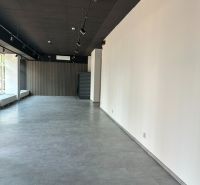 Prostorné kanceláře s podlahou s dřevěným dekorem, bílá stěna, elegantní osvětlení.