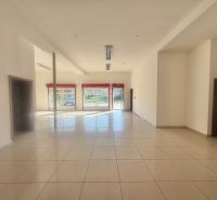 Světlé obchodní prostory s dlažbou a velkými okny poskytují dostatek přirozeného světla.