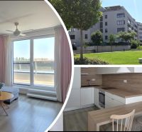 Obývací pokoj s pohovkou a balkonem, kuchyň a exteriér budovy se zelení.